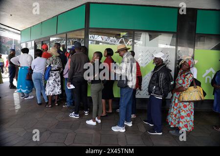 Harare, Zimbabwe. 30 avril 2024. Les gens font la queue pour retirer de nouvelles devises Zimbabwe Gold devant une banque à Harare, Zimbabwe, le 30 avril 2024. Les nouvelles pièces et billets Zig du Zimbabwe ont commencé à circuler mardi, marquant une étape importante dans la réforme monétaire du pays visant à freiner l'inflation trois semaines seulement après que la forme électronique de la monnaie a commencé à être commercialisée. Crédit : Shaun Jusa/Xinhua/Alamy Live News Banque D'Images