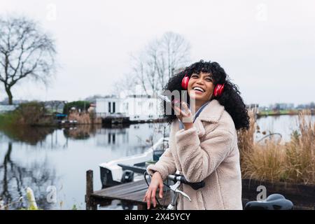 J'adorais les jeunes Afro-américaines au pelage chaud pour enregistrer des messages vocaux avec un smartphone et écouter de la musique dans un casque tout en vous refroidissant dans ci Banque D'Images