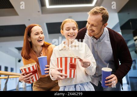 la famille tient joyeusement des tasses et du pop-corn tout en se liant lors d'une soirée cinéma familiale au cinéma. Banque D'Images