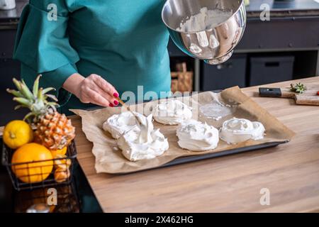 Dans une cuisine animée, un chef garnit méticuleusement une pavlova, faisant preuve de précision et d'art dans la préparation des desserts. Photo de haute qualité Banque D'Images