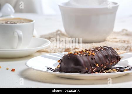 La nourriture est encore une vie dans le style d'une clé. Le gâteau au chocolat apparaît avec des noix sous forme de popsicle sur le bâton sur l'assiette et la tasse de café Prinspcino o Banque D'Images