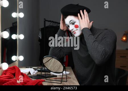 MIME artiste mettant sur le béret près du miroir dans le dressing Banque D'Images