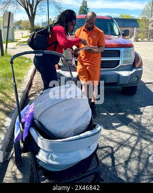 Racine, Wisconsin, États-Unis. 30 avril 2024. NADIA SIMMONS parle à DERRICK McIntyre alors qu'elle inscrit les électeurs dans un quartier afro-américain de racine, Wisconsin mardi 30 avril 2024. Elle a été embauchée pour le faire par une entreprise hors de la ville. Elle a rendu ses papiers à McIntyre, incapable de l'enregistrer, quand il lui a montré son permis de conduire de l'Illinois. SIMMONS a dit qu'elle travaillait de 10 à 6 jours par jour. Sa fille de cinq mois, LA REINE NEFETARI, est avec elle dans la poussette. (Crédit image : © Mark Hertzberg/ZUMA Press Wire) USAGE ÉDITORIAL SEULEMENT! Non destiné à UN USAGE commercial ! Banque D'Images