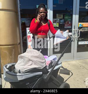 Racine, Wisconsin, États-Unis. 30 avril 2024. NADIA SIMMONS s'enregistre à son bureau alors qu'elle inscrit les électeurs dans un magasin / station-service pratique dans un quartier afro-américain de racine, Wisconsin mardi 30 avril 2024. Elle a été embauchée pour le faire par une entreprise hors de la ville. Sa fille de cinq mois, LA REINE NEFETARI, est avec elle dans la poussette. (Crédit image : © Mark Hertzberg/ZUMA Press Wire) USAGE ÉDITORIAL SEULEMENT! Non destiné à UN USAGE commercial ! Banque D'Images