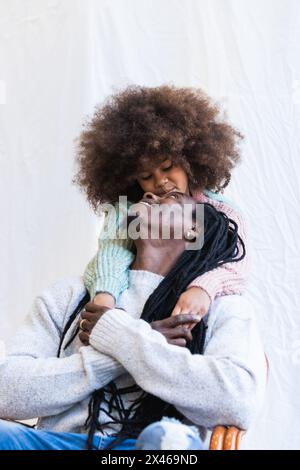 Heureux père Afro-américain embrassant sa fille tout en gardant les mains et en regardant les uns les autres Banque D'Images