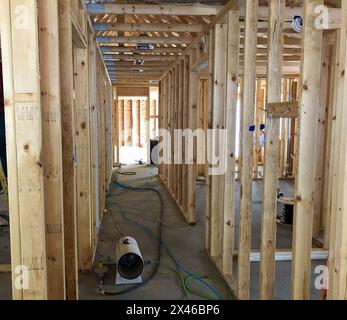 Poteaux de charpente en bois et chauffage électrique portatif sur plancher de béton dans un nouveau chantier de construction de maison. Banque D'Images