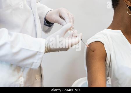 Gros plan de la récolte médique faisant l'injection pour la patiente noire Banque D'Images