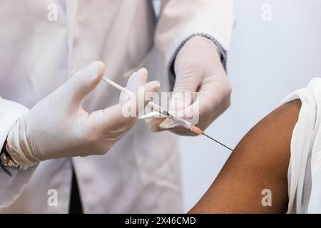 Gros plan de la récolte médique faisant l'injection pour la patiente noire Banque D'Images