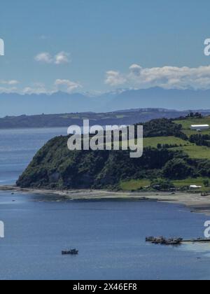 Les bateaux de pêche accostent dans la baie d'Achao sur l'île de Quinchao dans l'archipel de Chiloe au Chili. Derrière se trouvent les montagnes des Andes enneigées sur t Banque D'Images