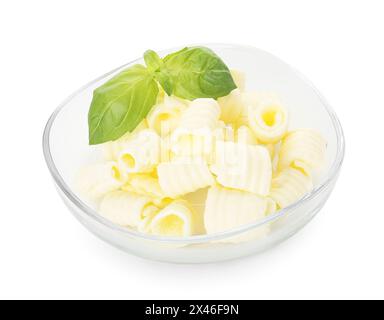 Savoureuses boucles de beurre et feuilles de basilic dans un bol isolé sur blanc Banque D'Images