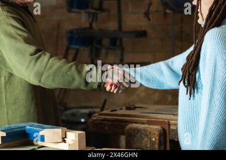 Vue latérale de la récolte anonyme femme client ayant affaire avec le menuisier créant des détails en bois dans la salle de travail Banque D'Images