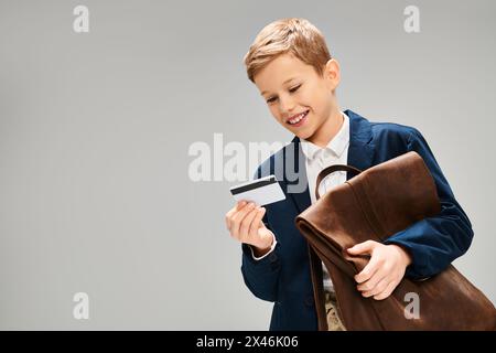 Garçon préadolescent dans une tenue élégante tenant mallette et carte de crédit. Banque D'Images