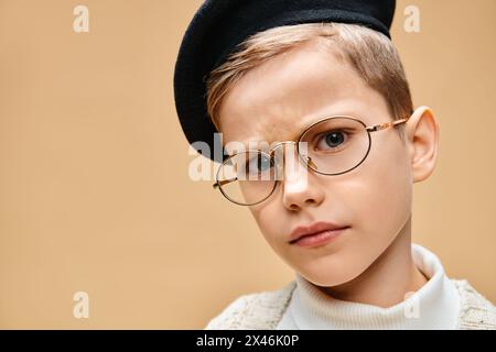 Un garçon préadolescent mignon habillé en réalisateur avec des lunettes et un chapeau. Banque D'Images