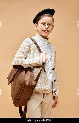 Un garçon préadolescent mignon habillé en réalisateur, portant des lunettes et un chapeau. Banque D'Images