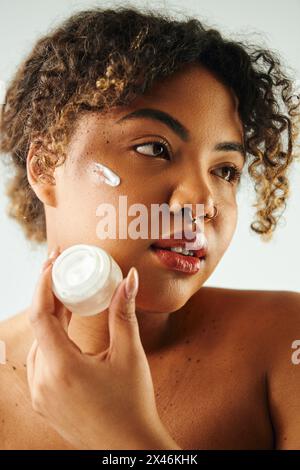 Femme applique gracieusement de la crème sur son visage. Banque D'Images