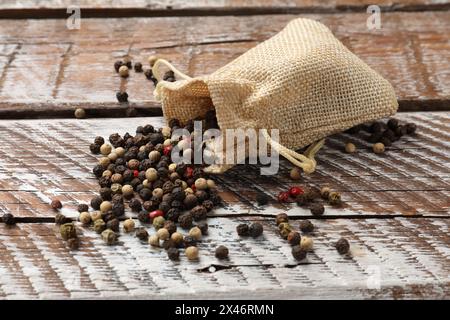 Épice aromatique. Différents poivrons dans un sac en toile de jute sur une table en bois Banque D'Images