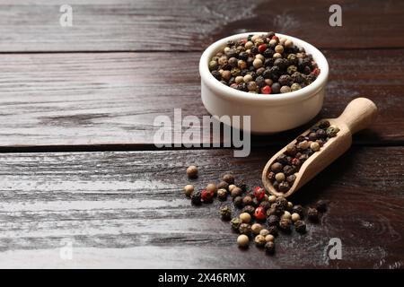 Épice aromatique. Différents poivrons dans un bol et une cuillère sur une table en bois, espace pour le texte Banque D'Images