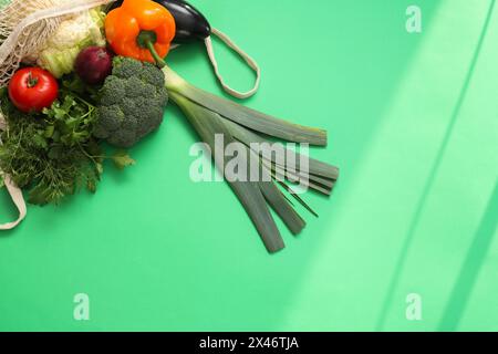 Sac à ficelle avec des légumes frais et des herbes sur fond vert, vue de dessus. Espace pour le texte Banque D'Images