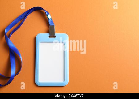 Badge vierge avec ficelle sur fond orange, vue de dessus. Espace pour le texte Banque D'Images