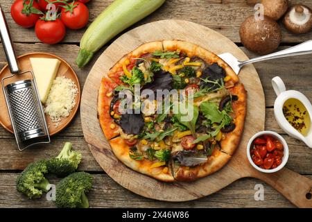 Délicieuse pizza végétarienne et ingrédients sur table en bois, plat Banque D'Images