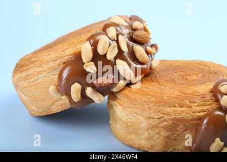 Croissants suprêmes avec de la pâte de chocolat et des noix sur fond bleu clair, gros plan. Pâte feuilletée savoureuse Banque D'Images