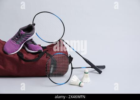Volants de badminton en plume, raquettes, sac et baskets sur fond gris Banque D'Images