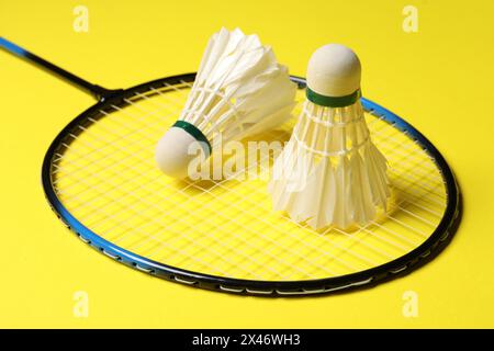 Volants de badminton de plume et raquette sur fond jaune, gros plan Banque D'Images