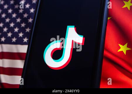 Vancouver, CANADA - avril 30 2024 : logo TikTok vu sur un écran d'iPhone sur le drapeau américain et le drapeau chinois Banque D'Images