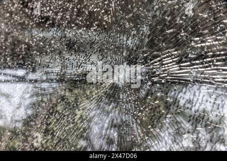 Pare-brise cassé d'une voiture gros plan comme arrière-plan. Texture verre cassé avec des fissures. Banque D'Images