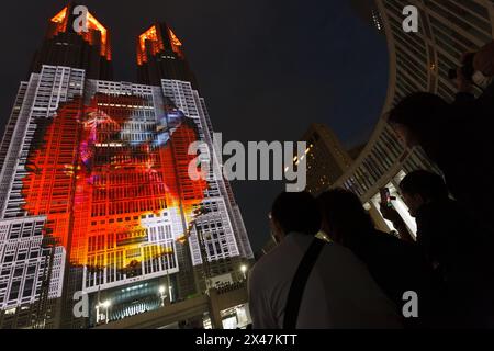 Tokyo, Japon. 29 avril 2024. Les gens regardent le spectacle Godzilla dans le cadre du projet de cartographie de projection Tokyo Night and Light à la tour 1 du gouvernement métropolitain de Tokyo à Shinjuku. Les expositions nocturnes du plus grand projet de cartographie permanente de projection du monde ont commencé en février 2024 et couvrent environ 13 905 m2 de la façade du monument de Tokyo. Une exposition mettant en vedette Godzilla attaquant Tokyo a été dévoilée le 27 avril 2024. Crédit : SOPA images Limited/Alamy Live News Banque D'Images