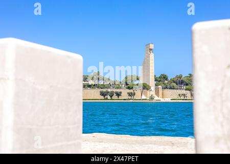 Grand monument du port de Brindisi regardant de la passerelle de lungomare par une chaude journée de printemps ensoleillée. Eau bleue et ciel clair, haute structure visible Banque D'Images