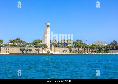 Grand monument du port de Brindisi regardant de la passerelle de lungomare par une chaude journée de printemps ensoleillée. Eau bleue et ciel clair, haute structure visible Banque D'Images