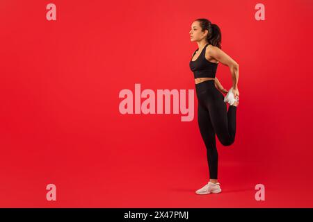 Fitness Lady effectue Quad Stretch sur fond rouge Banque D'Images