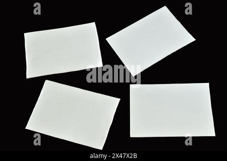 Sur un fond noir, quatre feuilles de papier blanc propre reposent chaotiquement. Banque D'Images