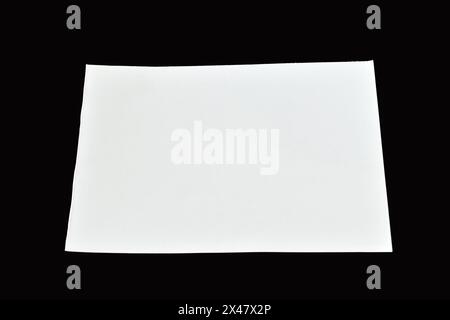 Sur un fond noir se trouve une feuille de papier blanche propre avec des bords droits. Banque D'Images
