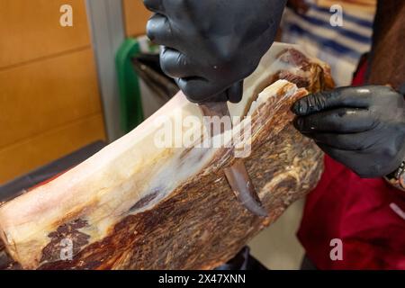 main d'un homme coupant le jambon, enlevant la graisse de la partie externe du jambon Banque D'Images