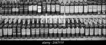 Différentes bouteilles d'alcool sont exposées sur les étagères du magasin. Diverses bouteilles d'alcool en vitrine en verre. Étagères avec bouteilles de vin rouge et blanc Banque D'Images