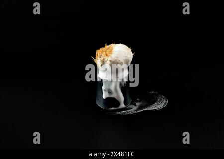 Sur un fond noir, il y a une vieille brosse à raser avec de la mousse à raser coulant le long. Banque D'Images