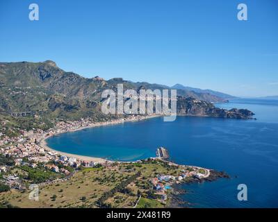 VUE AÉRIENNE. Les promontoires rocheux de Taormina se projetant dans la mer Ionienne. Ville métropolitaine de Messine, Sicile, Italie. Banque D'Images