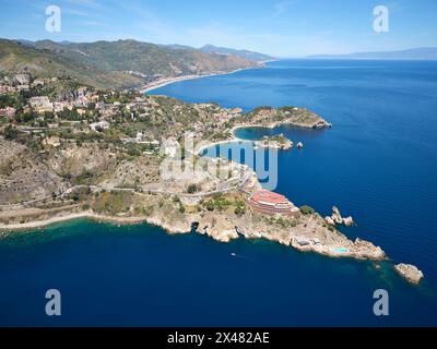 VUE AÉRIENNE. Les promontoires rocheux de Taormina se projetant dans la mer Ionienne. Ville métropolitaine de Messine, Sicile, Italie. Banque D'Images