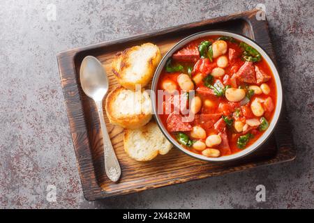 Ragoût épicé de haricots de lima, chorizo et épinards dans une sauce tomate gros plan dans un bol sur la table. Vue horizontale de dessus Banque D'Images