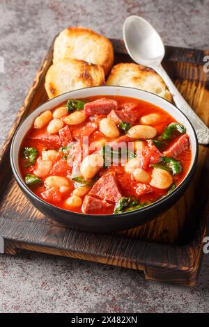 Chorizo, haricots rouges et épinards gros plan dans un bol servi avec du pain grillé sur la table. Vertical Banque D'Images