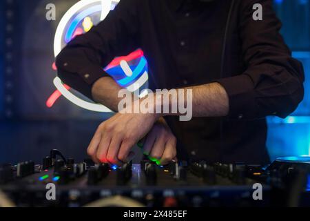 Vue rapprochée des mains d'un dj jouant la table de mixage pendant l'exécution Banque D'Images