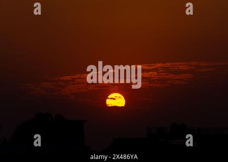 Découvrez la splendeur de la nature avec un coucher de soleil vibrant projetant une teinte orange sur la ville de Dehradun, Uttarakhand, Inde. L'envoûtement du paysage de nuages complète la Banque D'Images