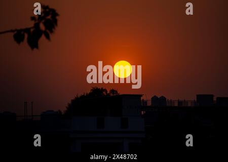 Découvrez la splendeur de la nature avec un coucher de soleil vibrant projetant une teinte orange sur la ville de Dehradun, Uttarakhand, Inde. L'envoûtement du paysage de nuages complète la Banque D'Images