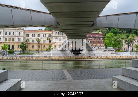 BILBAO, ESPAGNE - 10 MAI 2014 : la passerelle piétonne Pedro Arrupe sur la rivière Nervion à Bilbao, pays Basque, Espagne, avec l'Université de Deus Banque D'Images