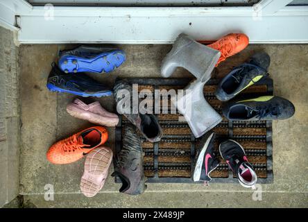 Assortiment de chaussures pour enfants déposé sur un seuil de porte avant. Banque D'Images