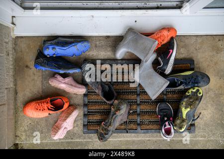 Assortiment de chaussures pour enfants déposé sur un seuil de porte avant. Banque D'Images