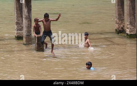 Dhaka. 1er mai 2024. Un garçon saute dans l’eau pour se rafraîchir à Dhaka, Bangladesh, le 30 avril 2024. Le Bangladesh a établi son record de températures extrêmes cette année alors que la canicule balaye de grandes parties du pays sud-asiatique. Le mercure a atteint 43,8 degrés Celsius mardi, dans le district sud-ouest du pays de Jessore, un record depuis 1989, selon le Département météorologique du Bangladesh (BMD). Crédit : Xinhua/Alamy Live News Banque D'Images