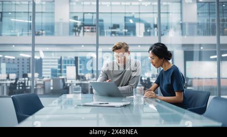 Salle de conférence multiethnique diverse Office : équipe de deux entrepreneurs créatifs discutent, discutent de la stratégie de croissance. Élégants jeunes gens d'affaires travaillent sur des projets d'investissement et de marketing. Banque D'Images